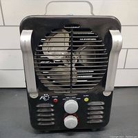 Full frontal view of the compact black space heater with silver handles and visible front protective grille and fan.