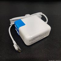 White Apple charger wrapped in blue protective film with connected white cable coiled neatly.