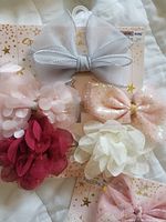 Two packages of hairbands with bows and floral decorations on display showing the full assortment of bows and flowers in pastel colors with silver sequin and glitter accents.