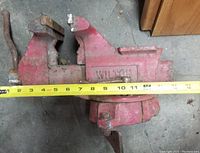 Front and side view of red Wilton bench vise showing brand name, jaw size, and measurement tape for scale.
