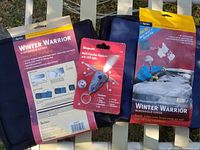 Photo showing packaging and items: two Winter Warrior windshield covers and one red and black Snap-on multi-function keychain with LED light in blister pack.