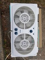 Holmes twin window fan, white plastic housing with two circular fans and control knobs on front.