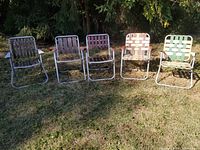 Full view of all five vintage folding lawn chairs set outdoors on grass, showing different types of seats and arms.
