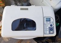 Top view of the Sunbeam bread machine showing lid with viewing window and control panel with digital timer and function buttons.