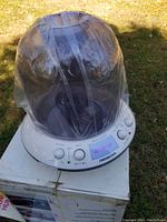 Ultrasonic humidifier outside with a plastic cover over it, resting on the original box.