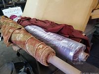Four rolls of upholstery fabric displayed on a table, showing colors and texture of each fabric.