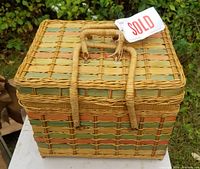 Front and top view of square vintage wicker basket showing natural and muted orange and green woven pattern and two looped handles