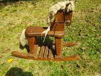 Wooden rocking horse viewed side on showing support runners and seat, yarn mane and tail, overall vintage wear