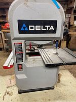 Front view of Delta band saw showing brand logo and work table surface.