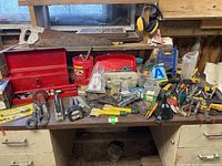 Overview of various hand tools and hardware items on a workbench, including saw, scissors, levels, tape measure, and power tools.