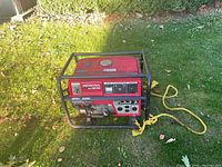 Front perspective showing red housing and black tubular steel frame of generator on grass