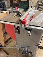 Full view of Craftsman table saw showing its large metal surface with red accents and part of the damaged stand leg.
