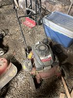 Photo of whole lawnmower showing red base, handle, and motor cover with some dirt and wear