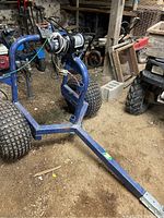 Full view of blue tubular steel log arch with mounted winch and tires