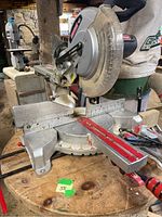 Full view of Craftsman mitre saw with red laser guide and accessories on wooden surface