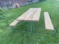 Full view of six-foot wooden picnic table with metal frame on grass, showing overall structure and benches.