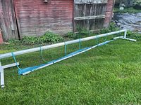 Full length side view of the manual aluminum pool cover reel with blue straps on the reel tube.