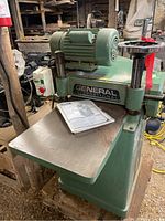 Front view of planer showing General International badge, cast iron table and manual on surface