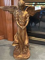 Front view of gold colour angel statue showing detailed wings, serene face, flowing robes, and hands clasped at waist.