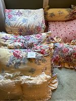 Floral comforter and matching pillow shams stacked on floor.