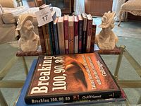 Photo of pair marble woman bust bookends holding a set of assorted coffee table books on glass table.