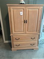 Front view of the Broyhill tallboy dresser armoire with two closed doors and two drawers below with metal handles.