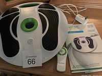 Revitive Circulation Booster device with remote control, power cord, and user manual shown on table.