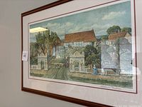 Full view of framed numbered print showing village scene with houses, people, trees, and gate structures under glass.