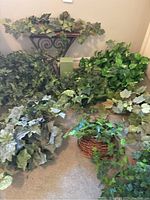 Overall lot of artificial ivy, foliage, and baskets laid out on carpet for display.