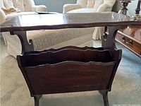 Front angle showing the magazine table with a dark stain wood finish and carved magazine rack compartment.
