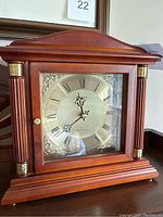Front view of the Bulova mantel clock showing the detailed face with roman numerals, decorative brass accents, and the wooden case.