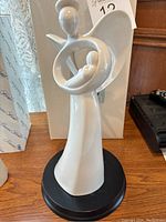 White abstract mother and baby ceramic figurine on black base, front and side views, with original box visible in background.