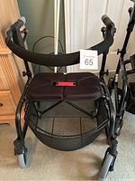 Front view showing cushioned seat, wire mesh basket beneath, padded hand grips, and front caster wheels.