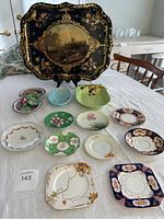 Overview photo of all plates and the large black enamel platter with stand on a table.