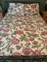 Queen bed with floral pink and green flower patterned reversible quilt and matching pillow shams.