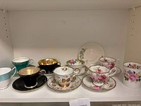 Front view of assorted cups, saucers, and mug on shelf