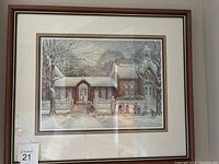 Framed print showing winter scene with children outside a brick building and white picket fence.