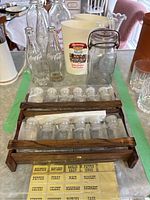Photo showing the 4 Coca-Cola bottles, 2 plastic white milk jugs with labels, one glass jar with wire bail, and spice rack with labeled small glass spice bottles.