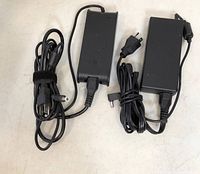 Photo of two black laptop chargers laid side by side, showing power cords and connectors.