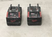 Front view of two Milwaukee M28 REDLITHIUM battery packs showing branding and front panels.