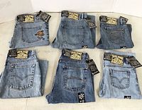 Photo showing six pairs of folded denim shorts arranged in two rows of three, showcasing various back pocket designs and brand tags from 5ive Jungle & Co.