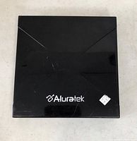 Top view of black Aluratek external DVD writer showing the brand logo and slightly scratched surface.