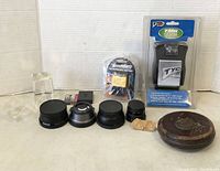 assorted camera lens adapters, batteries, charger, and leather case on white background