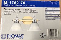 Box showing product image and details of polished brass and chrome two-light bathroom fixture model M-1762-70 by Thomas Lighting.