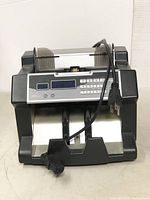 Front view of the bill counter showing keypad, display screen, and power cord placement