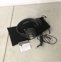 Blackweb wired headphones with cable, instruction manual, and soft carrying pouch on a white surface