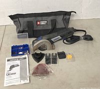 Full set includes Dremel Ultra-Saw, multiple blades, attachments, a small blue accessory box, instruction manual, and Porter Cable bag.
