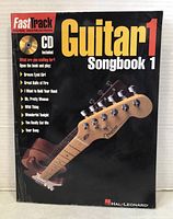 FastTrack Guitar 1 Songbook 1 instructional book cover featuring a Fender-style guitar headstock and included CD information.