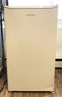 Closed front view of beige Hamilton Beach compact refrigerator showing minimal wear.