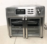 Stainless steel Kalorik Maxx Air Fryer Oven with dual doors closed, showing front control panel, digital LED display, and handles.